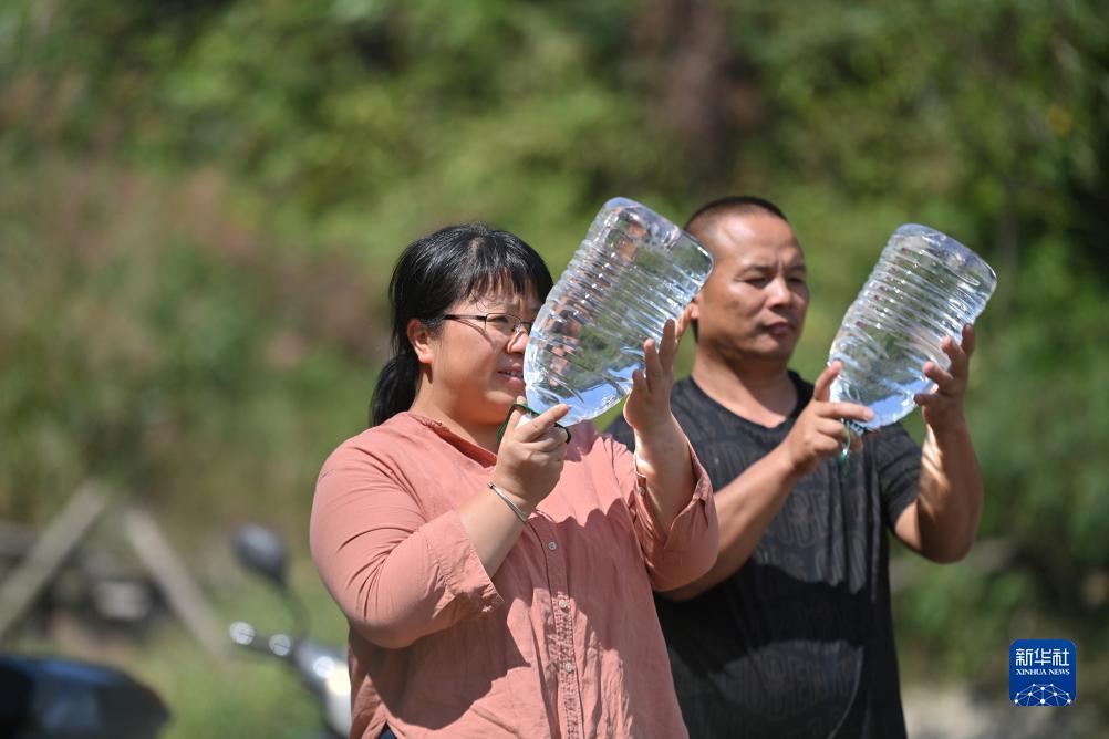 楊寧（左）在查看村民剛剛采集的水樣，為山泉水引水工程做準(zhǔn)備（10月8日攝）。新華社記者 黃孝邦 攝